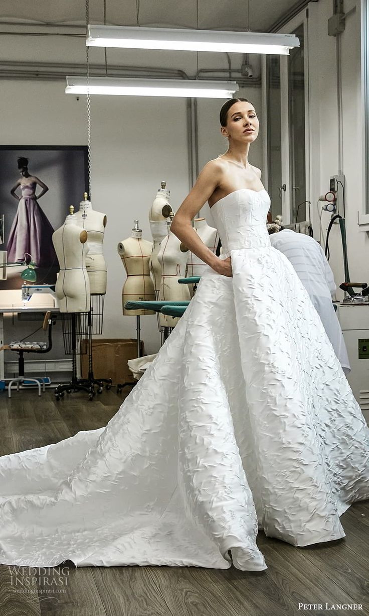 a woman in a white wedding dress standing next to mannequins