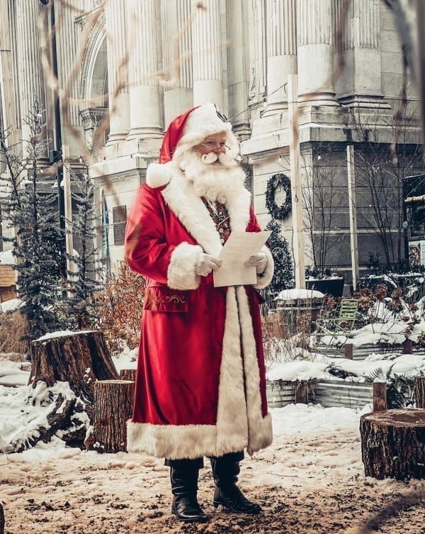 a man dressed as santa claus standing in the snow