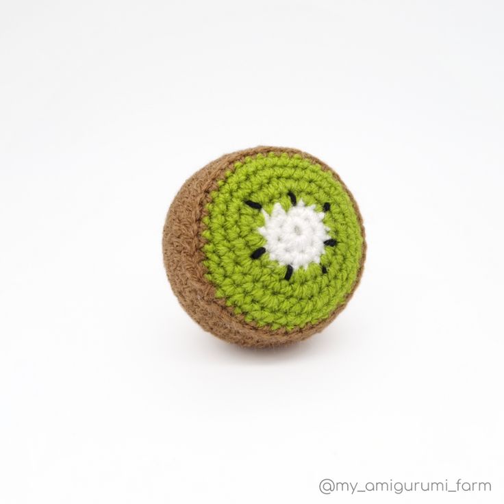 a crocheted green object with a white flower on it's center sits in front of a white background