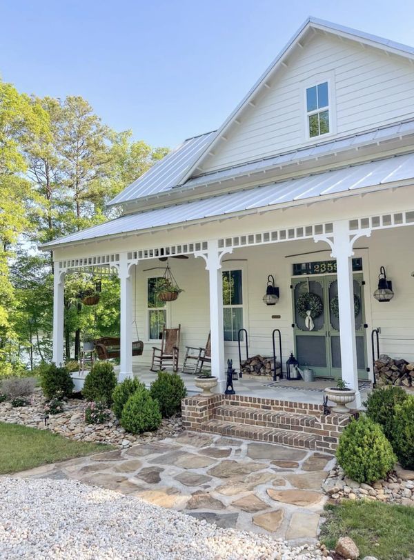 a white house with stone steps leading up to the front door and covered porch area