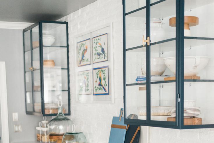 a kitchen with glass shelves and pictures on the wall