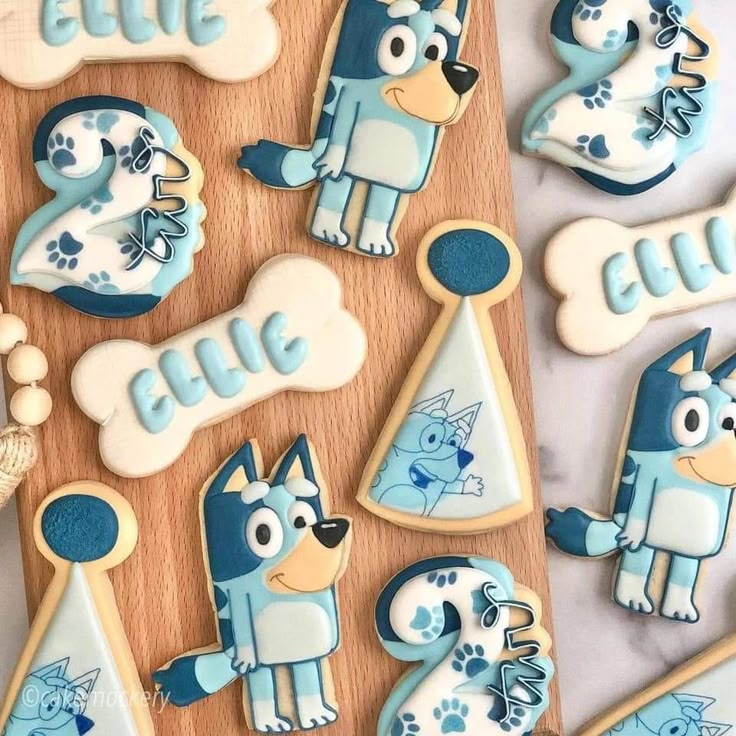 decorated cookies with blue and white frosting are on a wooden board next to other cookie decorations