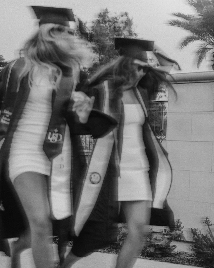 two women in graduation gowns walking down the street