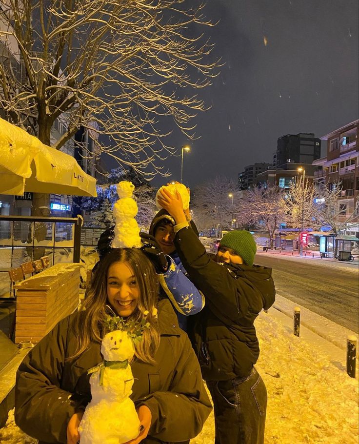 two people standing in the snow, one holding a stuffed animal and smiling at the camera