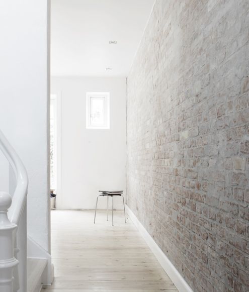 an empty hallway with white walls and wooden flooring next to a metal hand rail