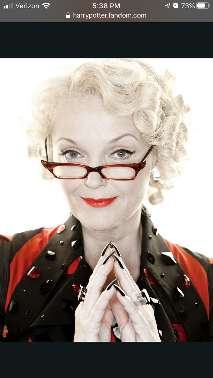 a woman with glasses and red lipstick holding her hands together in front of her face