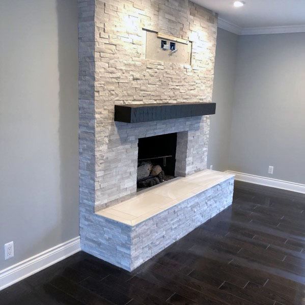 an empty living room with a fireplace in the middle and hard wood flooring on the other side