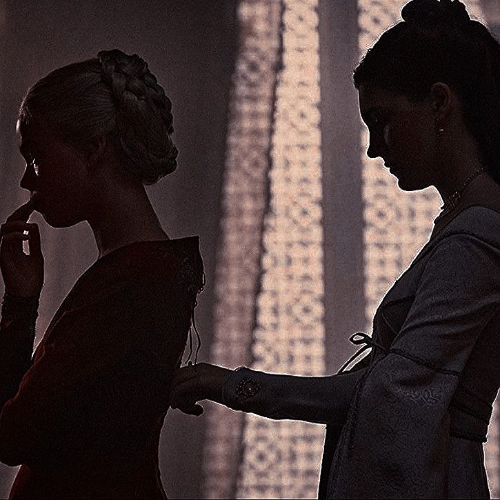 two women standing next to each other in front of curtains and talking on the phone