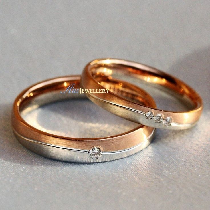 two gold wedding rings with diamond accents on the inside and outside, sitting next to each other