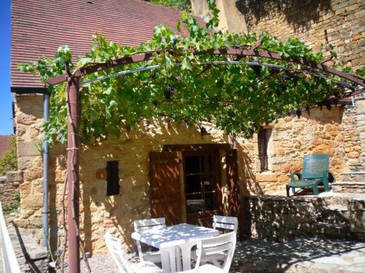 an outdoor dining area with table and chairs under a pergolated trellis over the patio