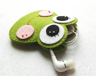 a green cell phone case with eyeballs and ear buds attached to the back of it