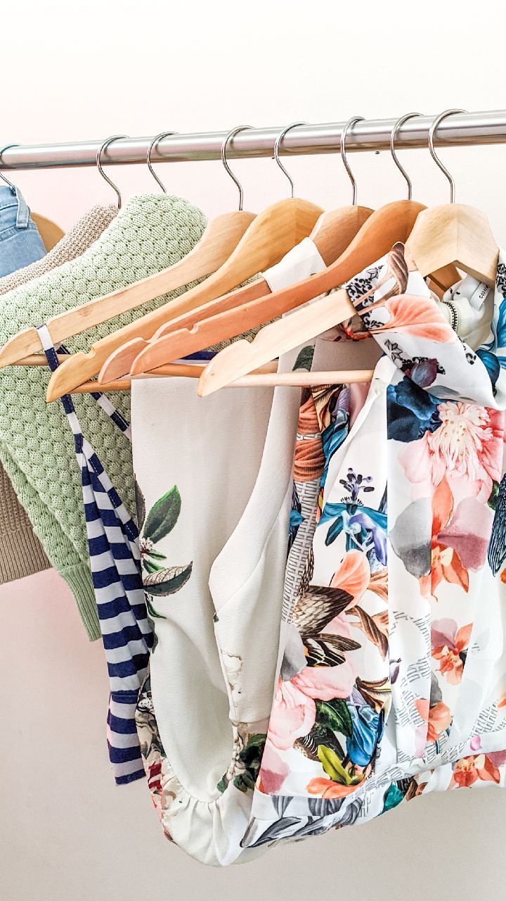 clothes hanging on a metal rack in front of a white wall, with several different colors and patterns