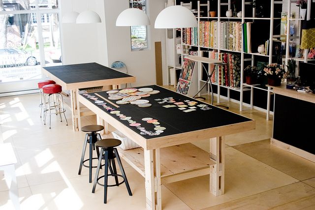 a room with tables, stools and shelves full of books in it's center