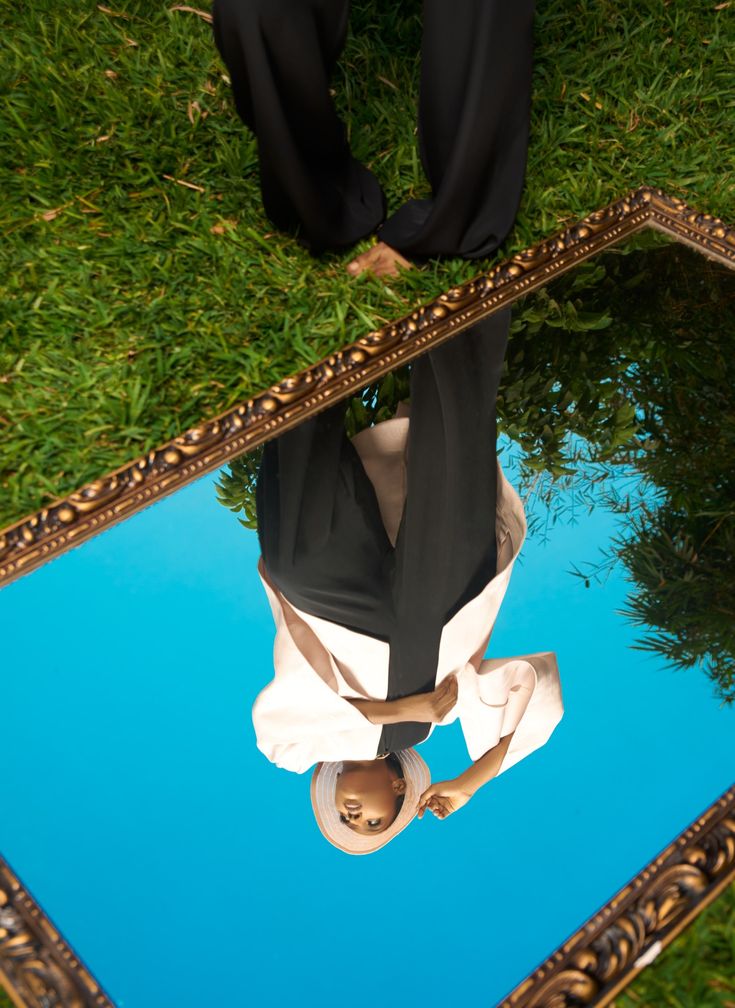 a reflection of a person in a mirror on the ground with their feet propped up