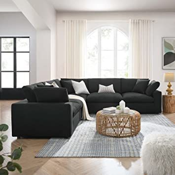 a living room with black couches and white rugs