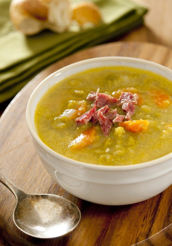 a white bowl filled with soup on top of a wooden table next to a spoon