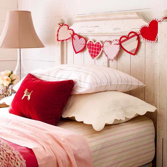 a bed topped with lots of pillows next to a lamp