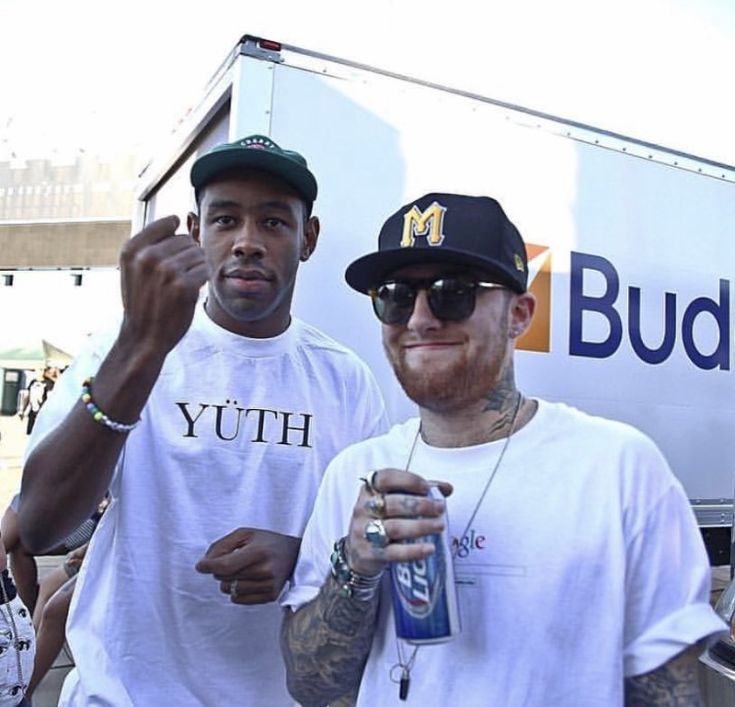 two men standing next to each other in front of a truck