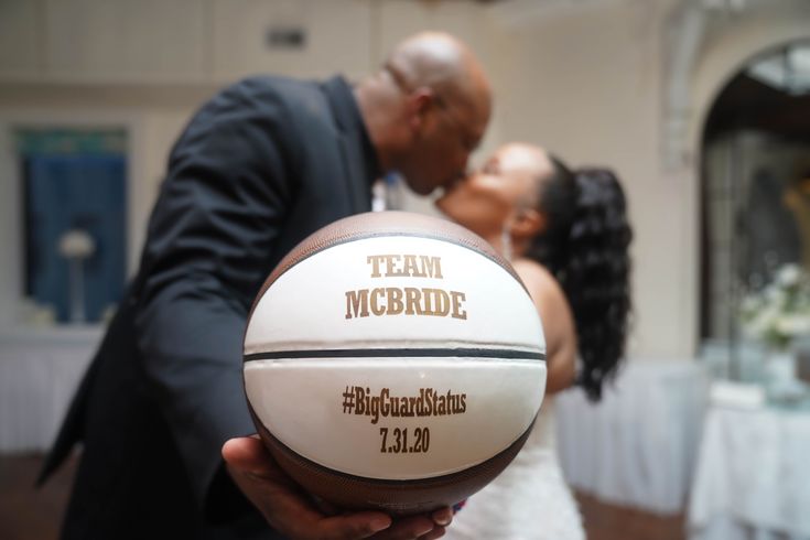 a bride and groom kissing while holding a basketball