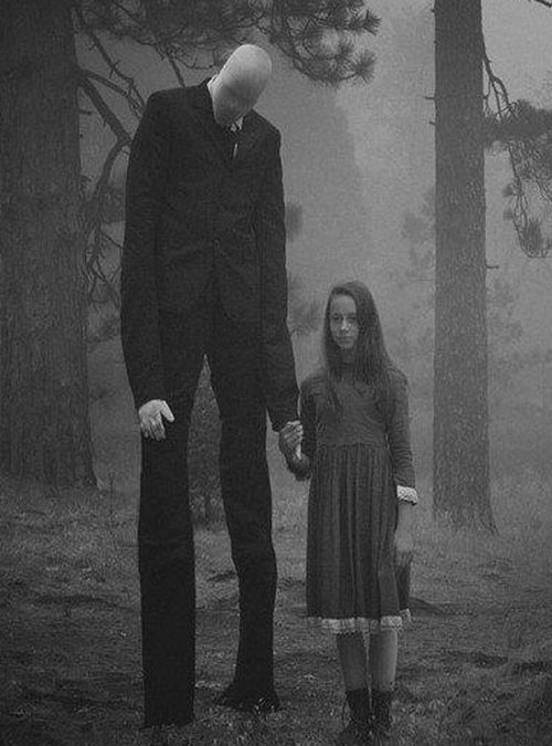 two people standing next to each other in the woods with trees and fog behind them