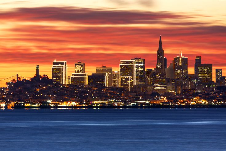 the city skyline is lit up at night as seen from across the water in san francisco, california