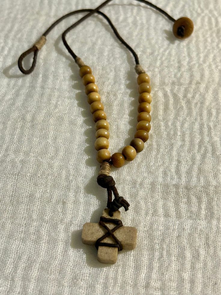 Add a unique touch to your wardrobe with this vintage tribal cord necklace. The brown beaded design features a charming stone cross pendant, making it a perfect accessory for any occasion. With a necklace length of 18 inches and a button closure, it is suitable for both men and women. The necklace has a beaded style and a pendant/locket type of charm, adding a touch of elegance to your outfit. The chain type is cord, and the country of origin and manufacture are unknown. The necklace is ideal for those who appreciate ethnic, regional, and tribal jewelry. Beaded Spiritual Cross Pendant Necklace, Spiritual Beaded Cross Pendant Necklace, Casual Brown Necklace With Adjustable Cord, Adjustable Bohemian Cross Beaded Necklaces, Bohemian Cross-shaped Beaded Necklaces, Bohemian Beaded Cross Necklace, Brown Bohemian Cross Necklace, Bohemian Brown Cross Necklace, Bohemian Beaded Cross Pendant Jewelry