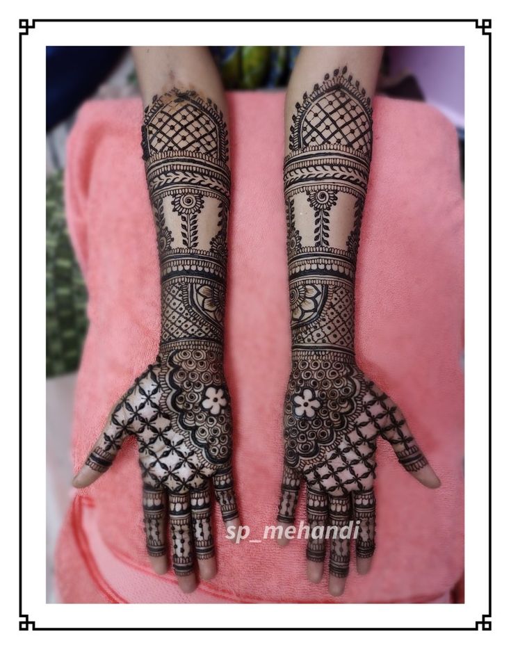 two hands with henna tattoos on them, one is showing off the intricate design