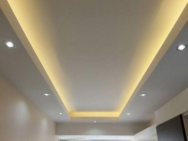 an empty living room with white walls and lights on the ceiling is lit by recessed lighting