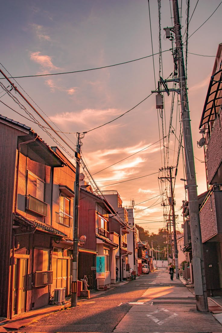 an alley way with buildings and power lines in the background at sunset or sunrise time