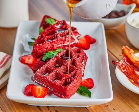 the waffles are being drizzled with syrup and strawberries on the plate