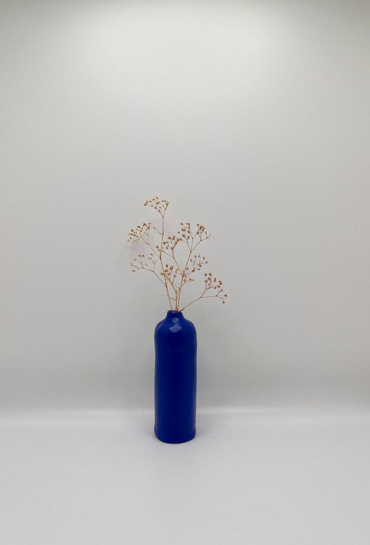 a blue vase filled with flowers on top of a white table next to a wall