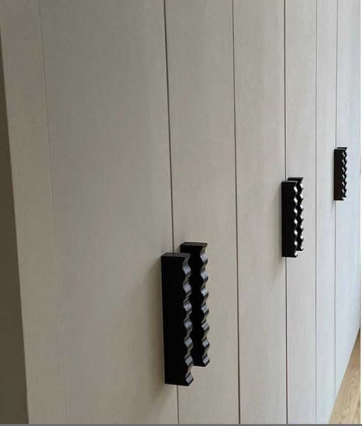 three black handles on white cabinets in a room