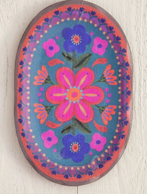 a painted plate with flowers on it hanging on a wall next to a wooden plank