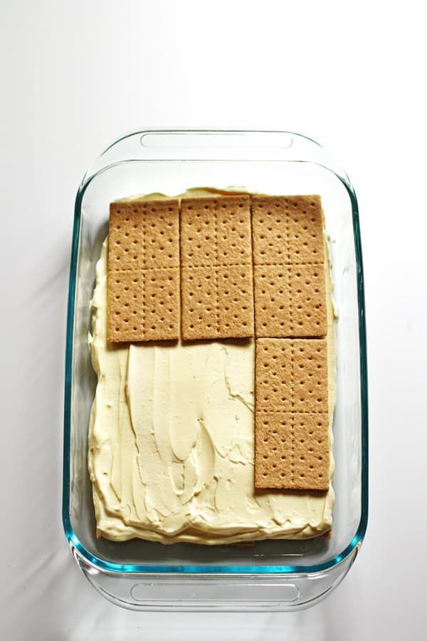 a cake with graham crackers on it in a glass dish