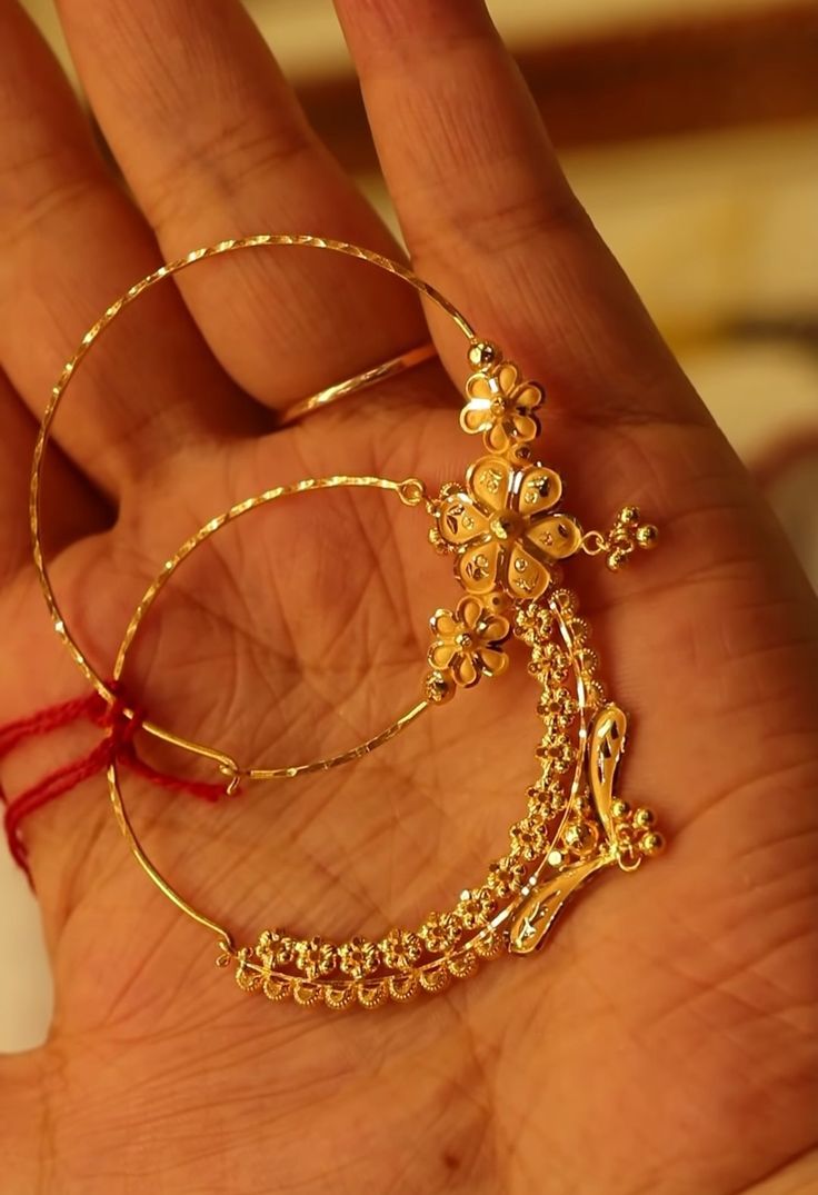 a person is holding some gold jewelry in their hand