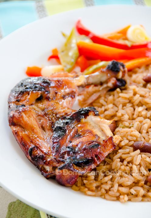 a white plate topped with rice and meat next to veggies on a table