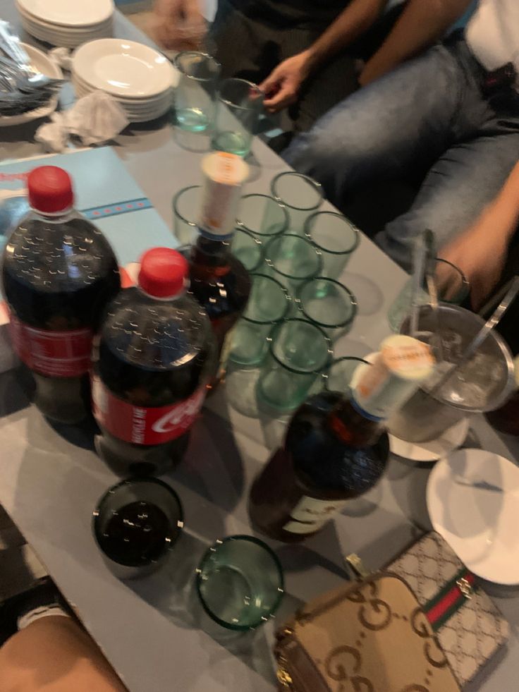 people sitting at a table with many empty bottles and glasses on top of the table