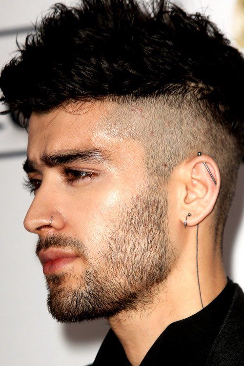 a close up of a person with a shaved head and ear piercings on his ears