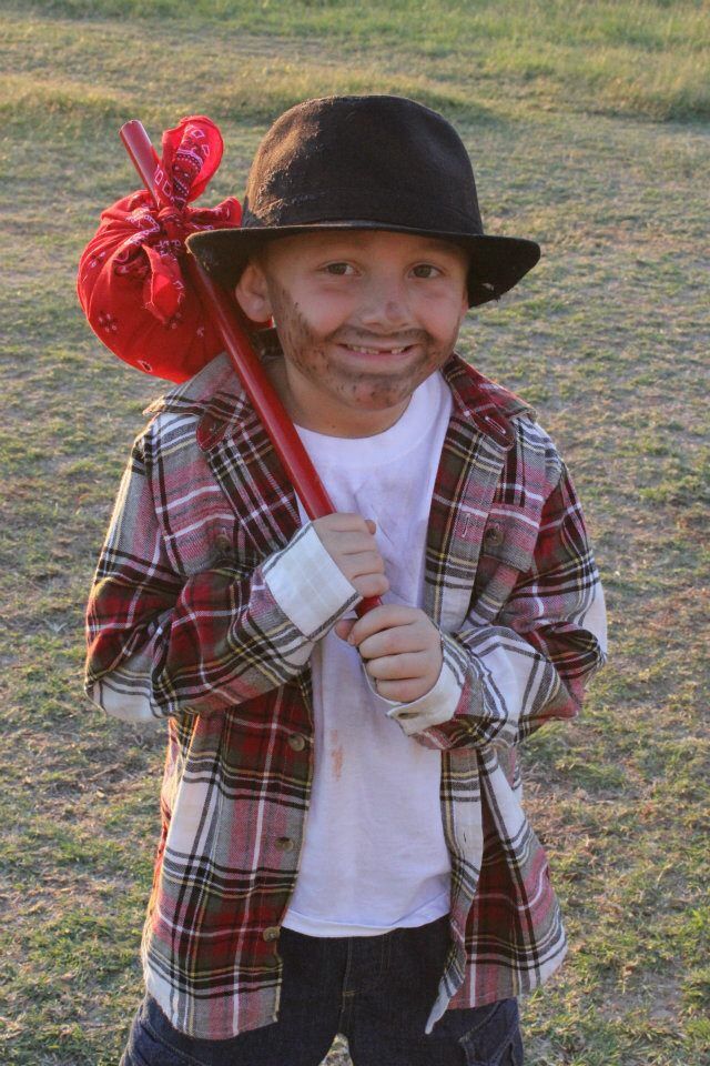 a young boy holding a red baseball bat in his hand and wearing a plaid jacket