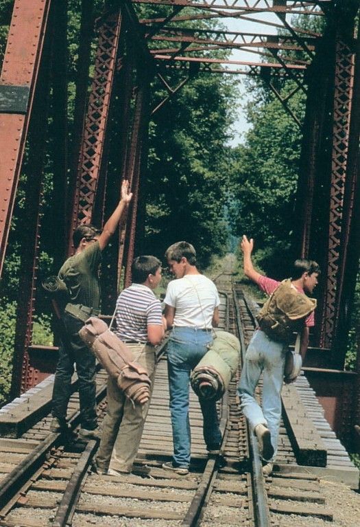 four people walking across a bridge with their arms in the air