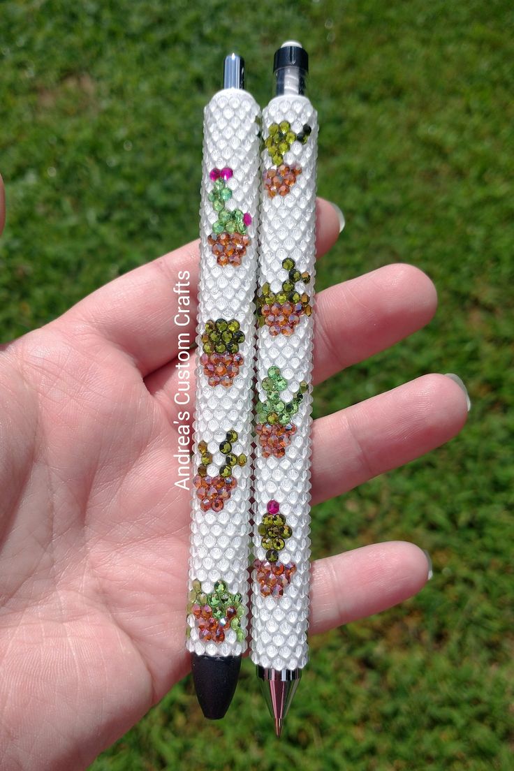 two white beads with flowers on them are held in someone's hand