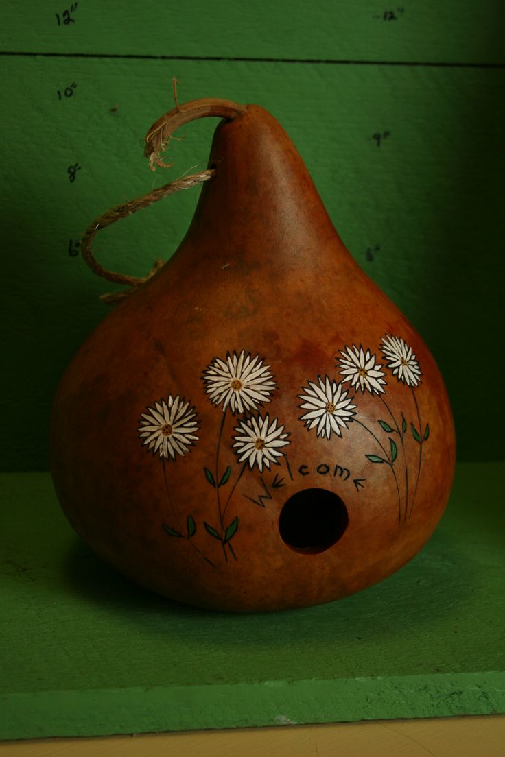 a brown vase with white flowers on it sitting on a green shelf next to a wall