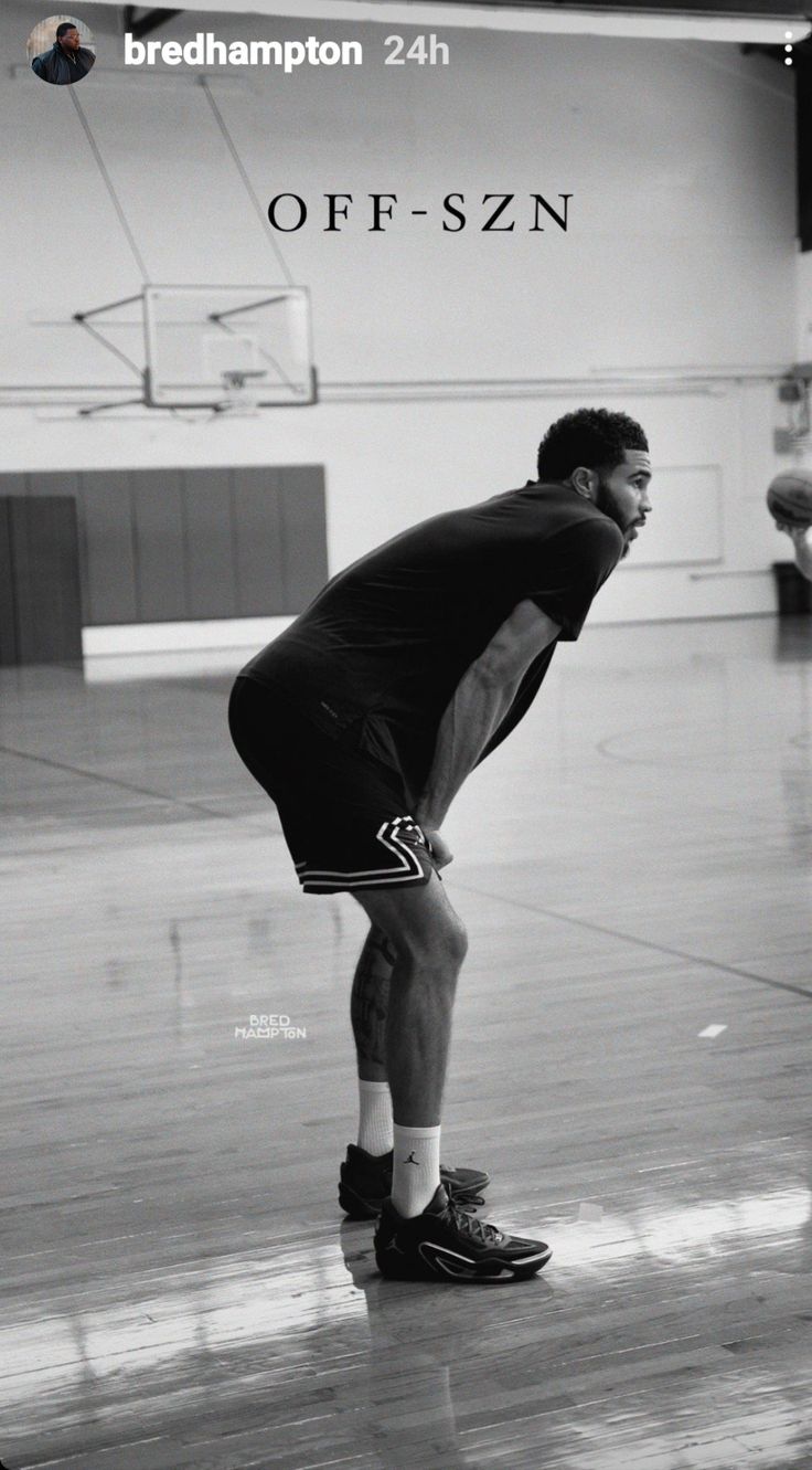 a man standing on top of a basketball court holding a ball in one hand and looking down at the ground