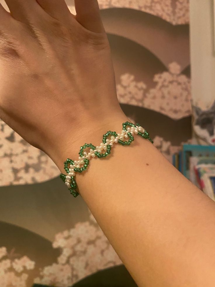 a woman's hand with a green and white beaded bracelet on her wrist