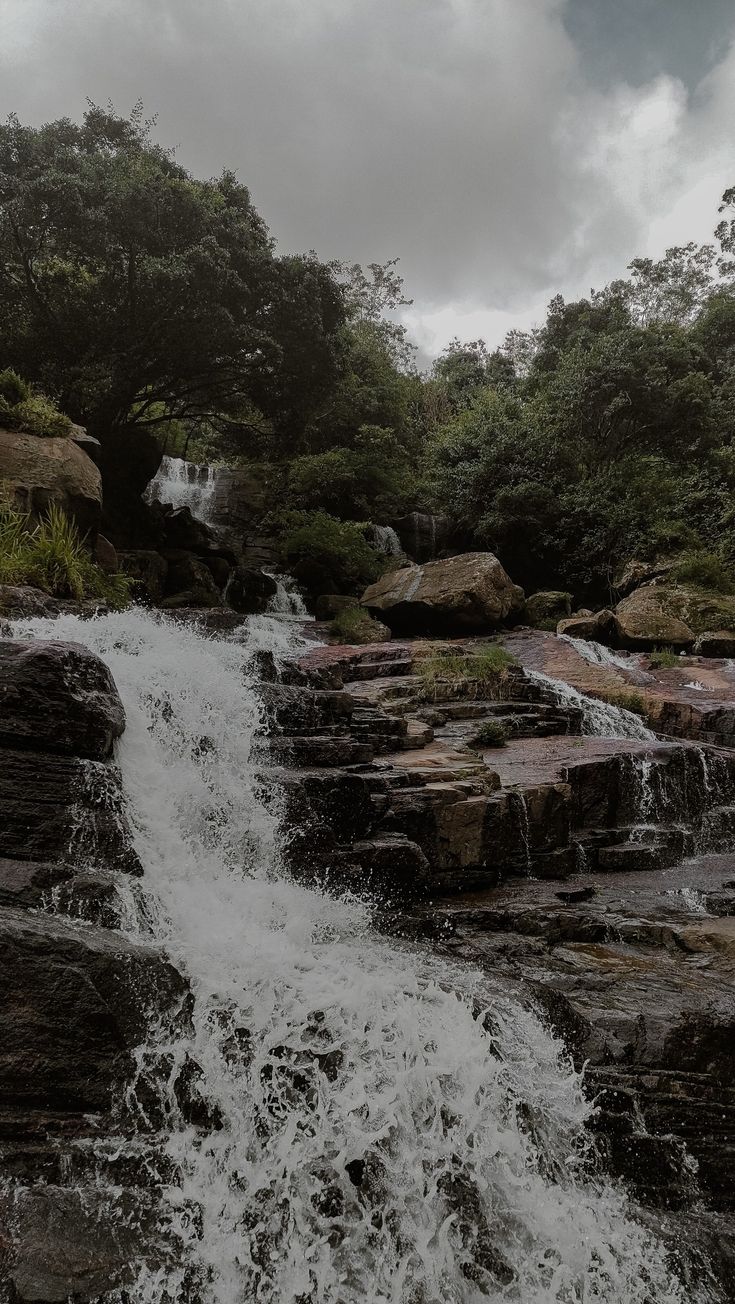 there is a waterfall in the middle of some rocks and water flowing down it's sides