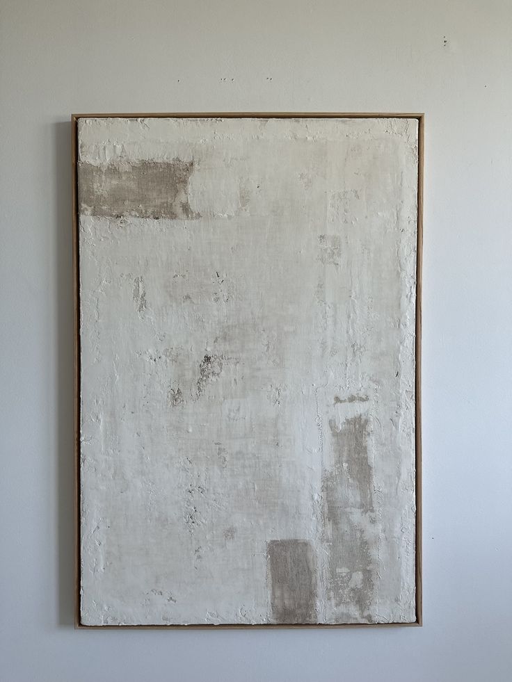 an abstract painting hangs on the wall in front of a white wall with a wooden frame