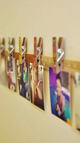 several photos hanging on a wall with a measuring tape attached to the pegs that hold them