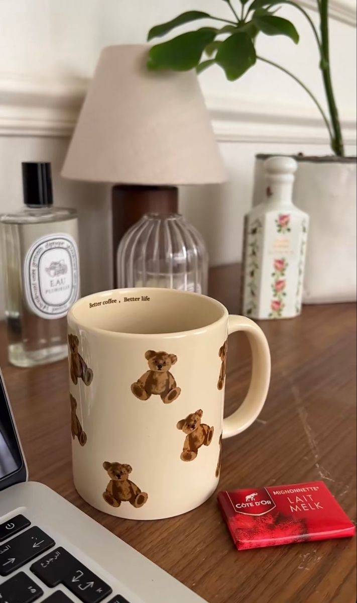 a laptop computer sitting on top of a wooden desk next to a coffee cup and candy bar