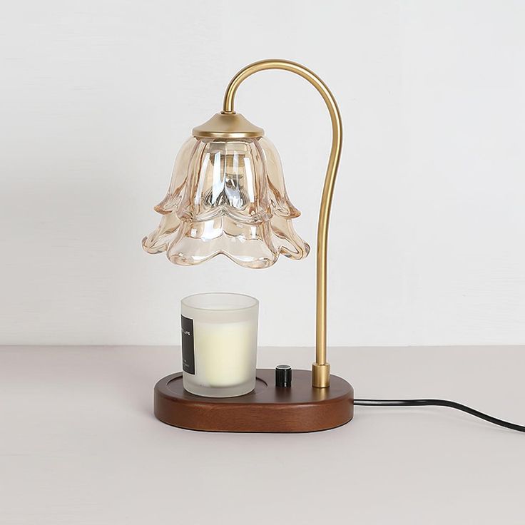 a table lamp with a glass candle on it and a wooden stand in front of it