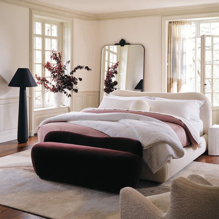 a large bed sitting in a bedroom on top of a hard wood floor next to two windows